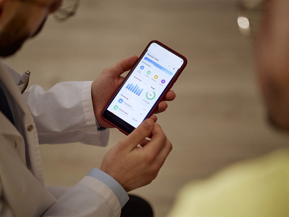 Clinician reviewing glucose care and metabolic health data on smartphone during patient consultation